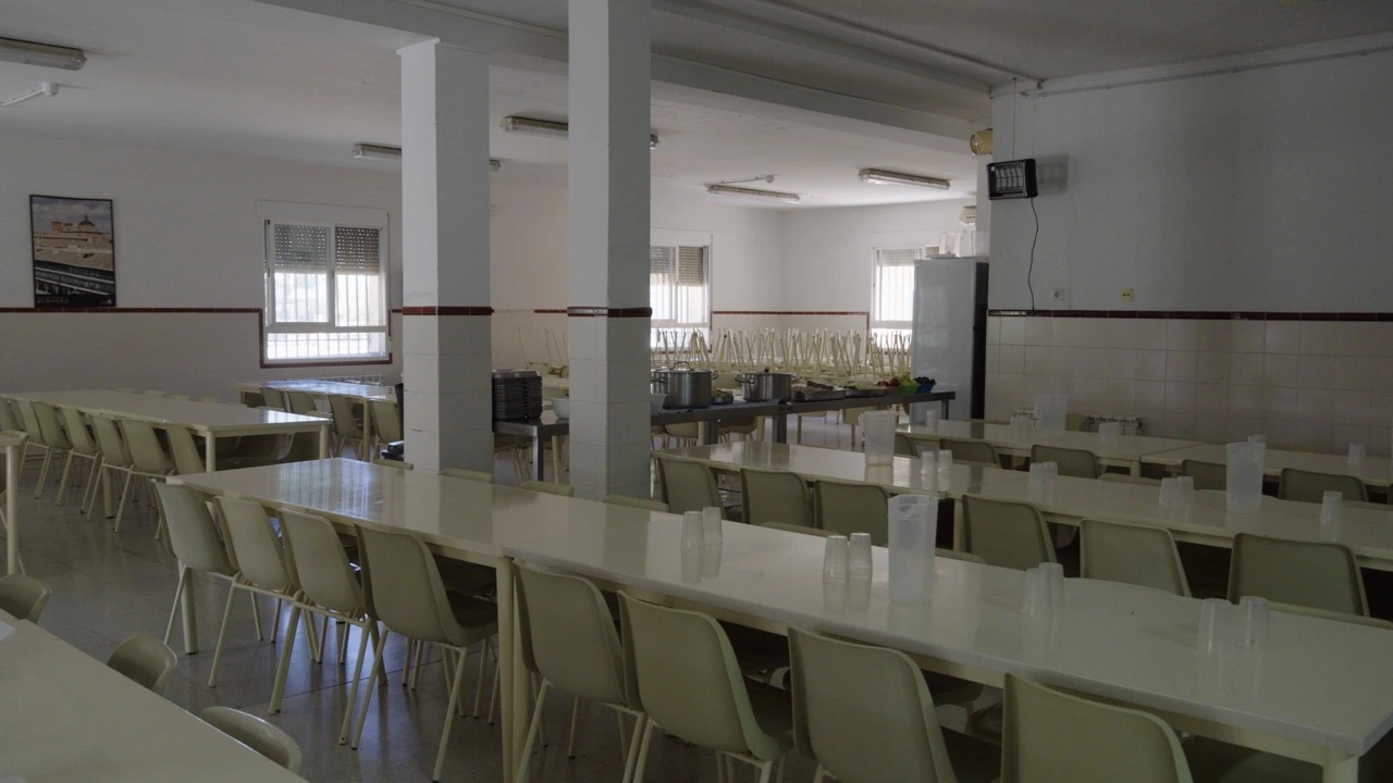 Comedor de Orea con mesas largas, sillas y zona de servicio al fondo