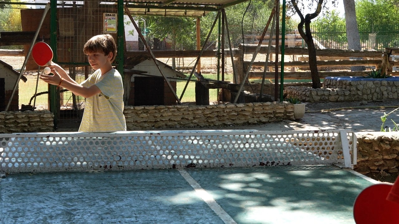Participante jugando al ping-pong bajo los árboles de Orea